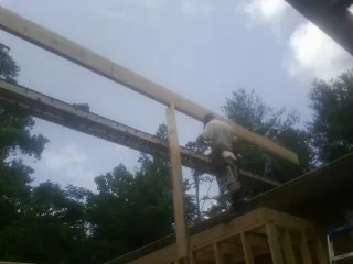 Carpenter setting a ridge beam over a new addition frame — Ice Dam Removal by Roofing Brothers in Iselin