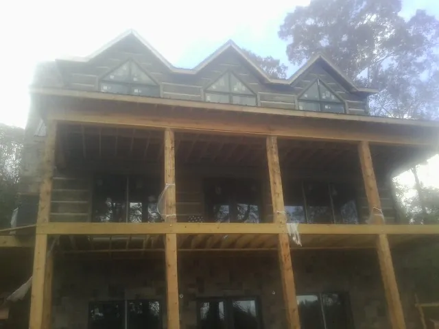 Dormers and porch framing on a large log home under construction — Roof Coating work by our crew in Iselin