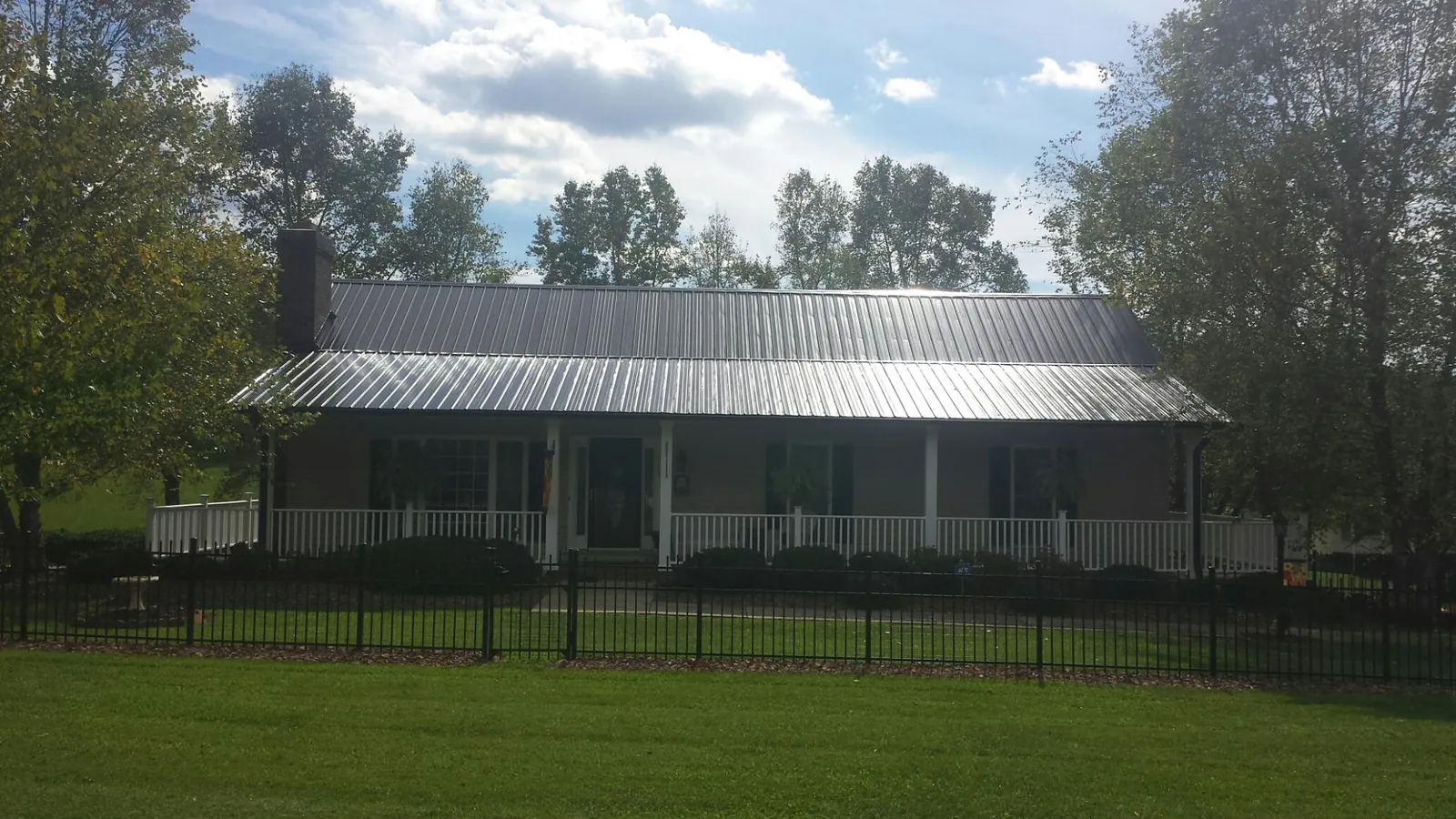 Gray metal roof on a brick ranch with a full width front porch — Gutter Guard Installation work by our crew in Iselin