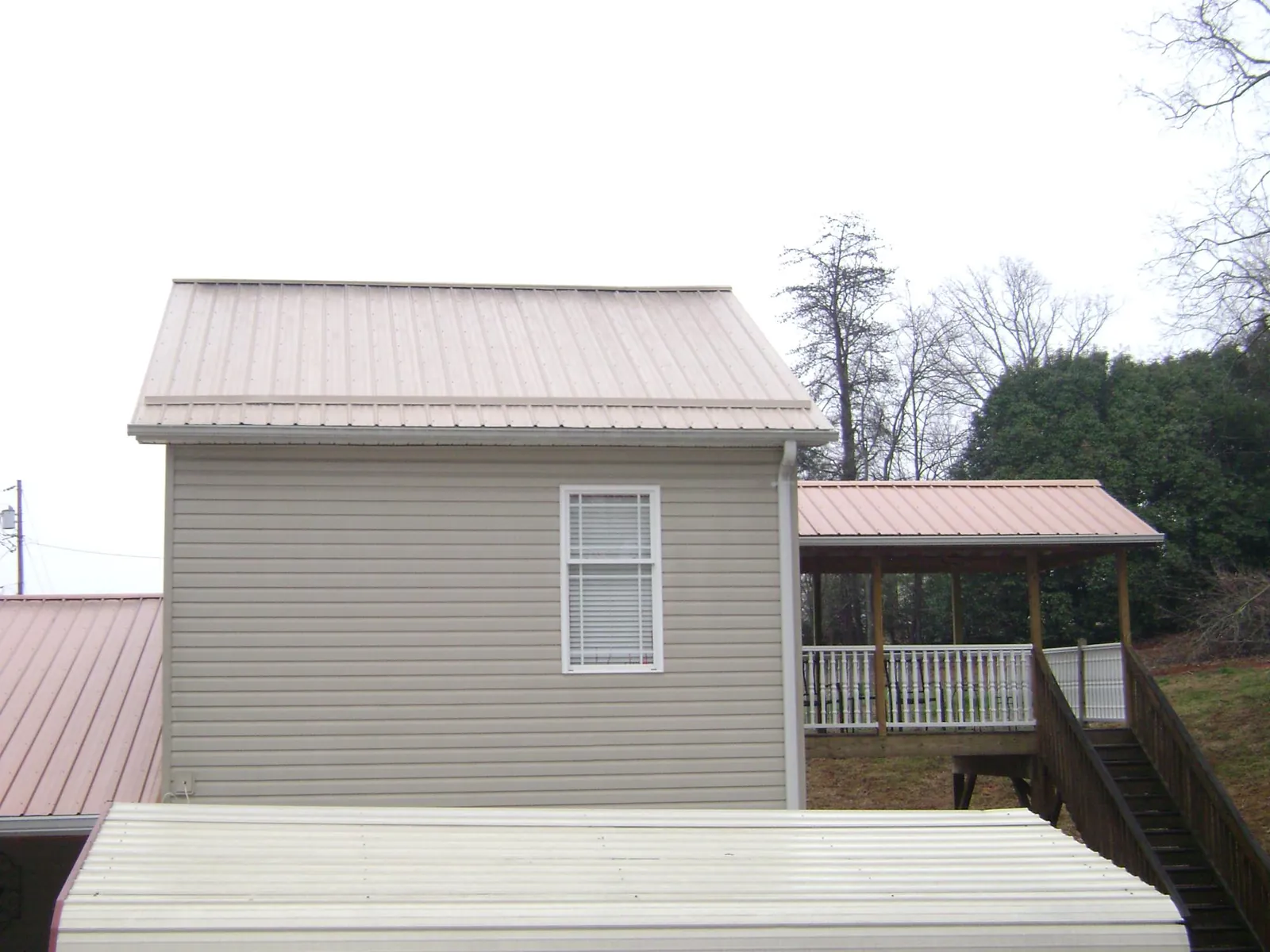Tan metal roofs on a two story addition and attached porch, from a Roof Replacement job in Iselin