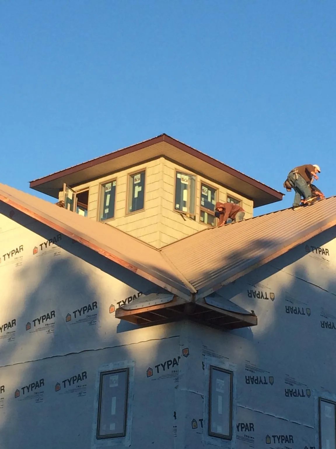 Roofers working around a rooftop cupola on a new metal roof at sunset — Roof Waterproofing in Iselin by Roofing Brothers